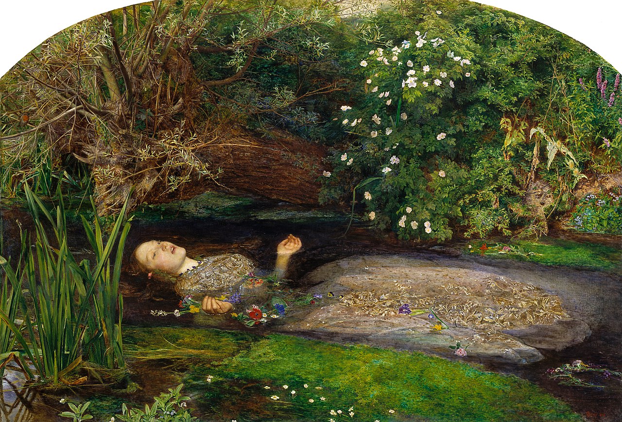 a woman in a beautiful dress sinks into a creek surrounded by foliage